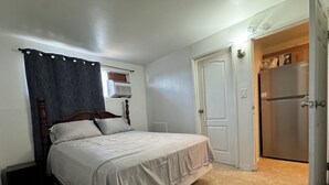 Een slaapkamer met een bed, een deur en een koelkast.