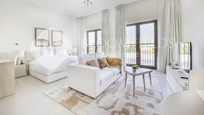 A modern hotel room with a bed, a sofa, a small table, and a balcony with curtains. - 224-Bloomfields Modern Stu Yas Golf  (Abu Dhabi)