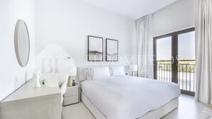 A modern hotel bedroom with a large bed, a bedside table, a mirror, and a view of the outdoors through a sliding glass door. - 224-Bloomfields Modern Stu Yas Golf  (Abu Dhabi)