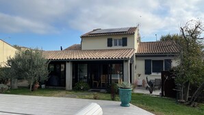 A two-story house with a tiled roof, a covered patio, and a swimming pool. - Charming villa for a vacation in the south of France (Uzès)