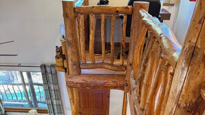 A wooden staircase with a railing, leading to a room with a desk and a window. - Woodsy Cozy Escape, Finest Mountain Vibes, Hot Tub, Pirate Ship and Xbox (Big Bear City)