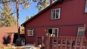 A hot tub with a wooden deck and a red building in the background. - Woodsy Cozy Escape, Finest Mountain Vibes, Hot Tub, Pirate Ship and Xbox (Big Bear City)