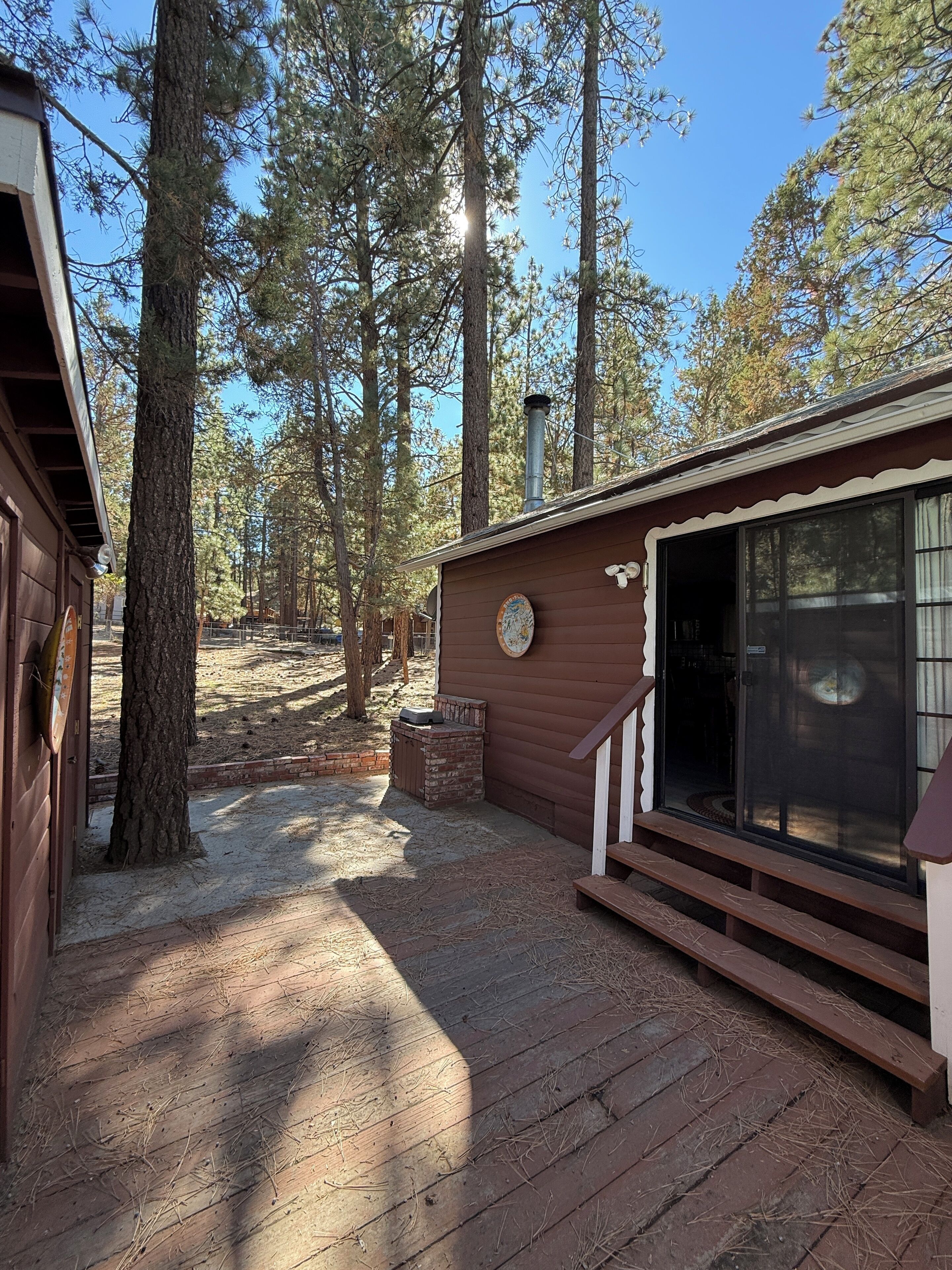 A cabin with a wooden deck, a brick fireplace, and a large window.