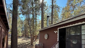 A cabin with a wooden deck, a brick fireplace, and a large window. - Goldilocks Mountain Vibes for All Your Bears - No Better than Our Relaxing Mountain Vibes Cabin, 3BR for Mamma, Papa, and Baby Bears! (Big Bear)