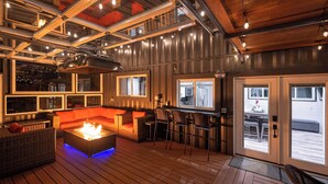Un amplio espacio exterior con una chimenea, asientos y una zona de bar.