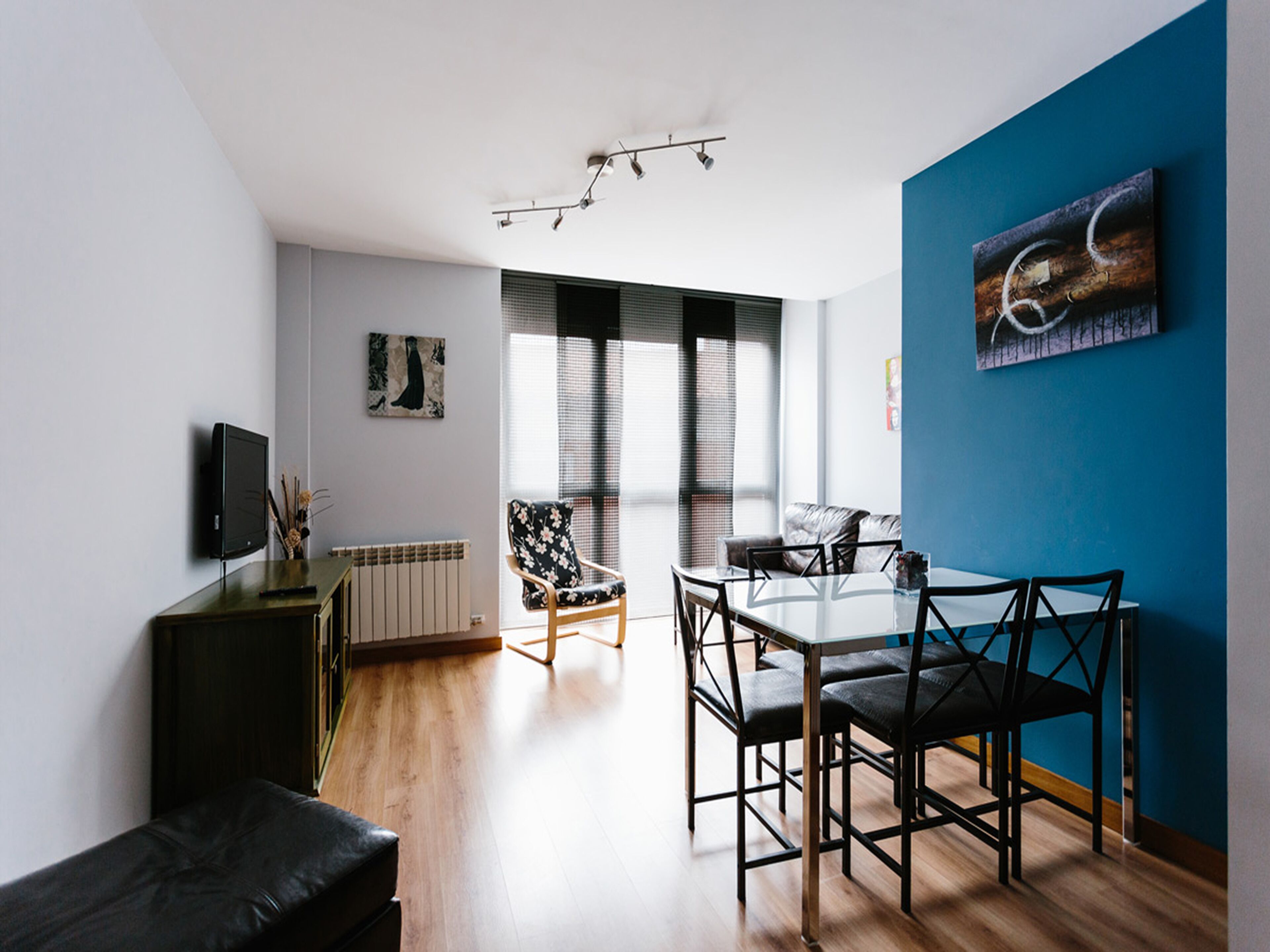 Una sala moderna con comedor, que incluye un sofá, una mesa con sillas, un radiador y obras de arte en las paredes.