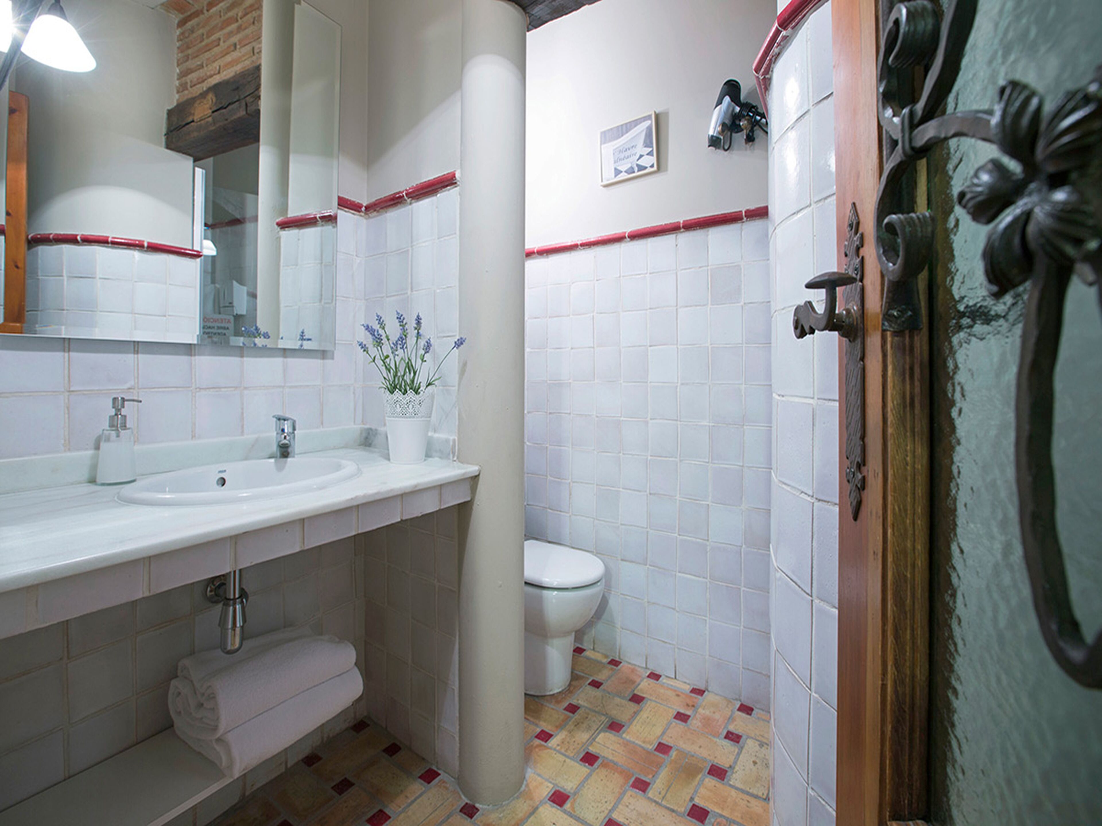 A bathroom with a white sink, mirror, and toilet, a towel rack, and a decorative plant.