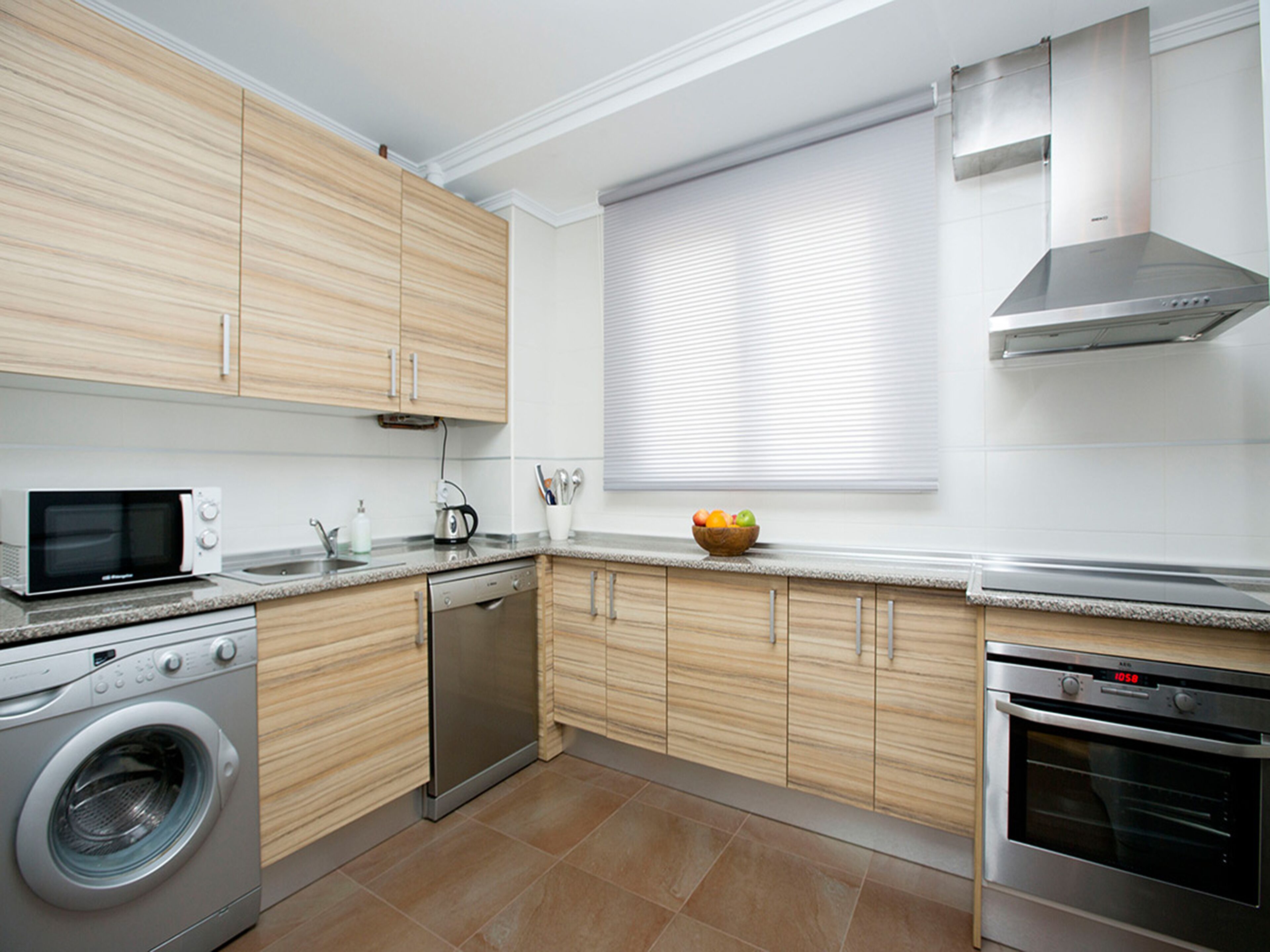 A modern kitchen with wooden cabinets, a built-in microwave, a dishwasher, and an oven.