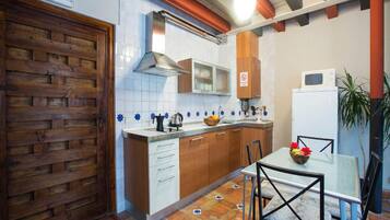 A compact kitchen with white cabinets, a wooden door, and a tiled backsplash.