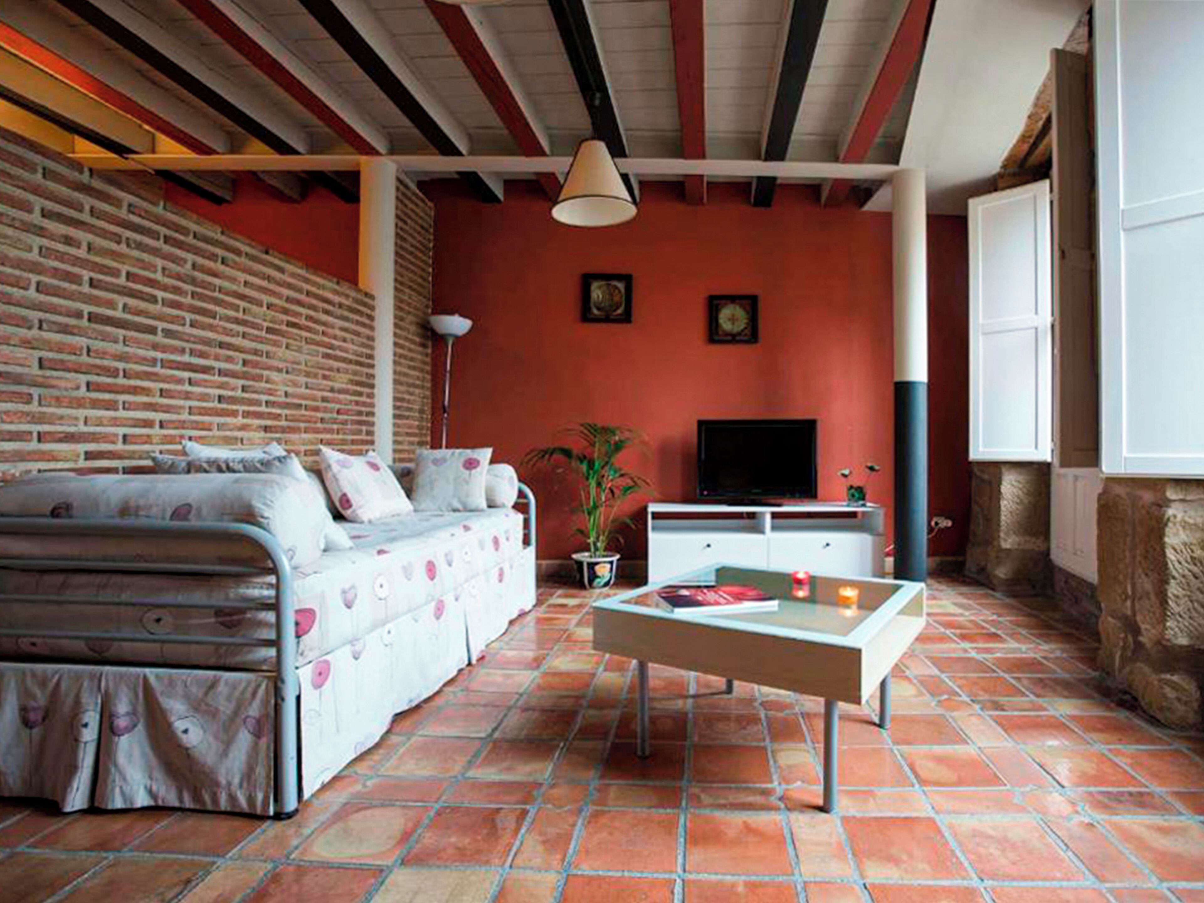 Un salon chaleureux avec un canapé, une table basse, un téléviseur et un mur en briques.