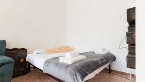 Une chambre à coucher comprenant un lit, une commode, une chaise et une étagère fixée au mur.