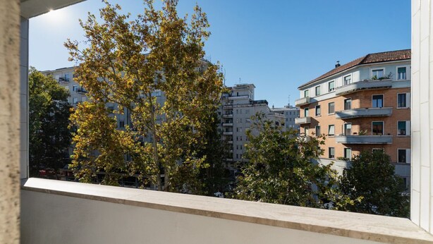 Une vue sur un paysage urbain avec des immeubles à plusieurs étages, un arbre et un ciel dégagé.