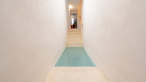 Un estrecho pasillo con piso azul claro que conduce a una escalera.