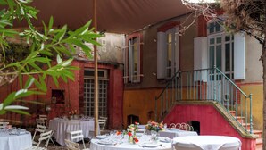 An outdoor dining area with round tables set for a meal, surrounded by white chairs. - Maison Bonnefoy Toulouse (Toulouse)