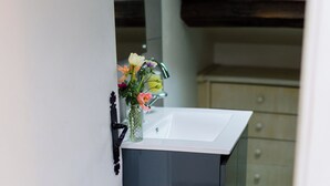 A bathroom with a white sink, a mirror, and a vase with flowers. - Maison Bonnefoy Toulouse (Toulouse)