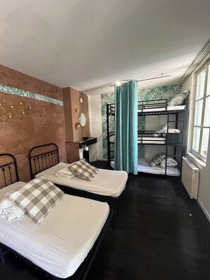 A room with two beds, a window, a radiator, and a bunk bed in the background. - Maison Bonnefoy Toulouse (Toulouse)