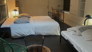 A room with two beds, a small table, a chair, and a wall-mounted TV. - Maison Bonnefoy Toulouse (Toulouse)