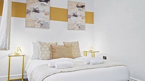A hotel room with a bed, two bedside tables, and two wall-mounted artworks.