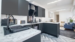 A modern kitchen with dark cabinetry, a built-in stove, and a marble countertop.