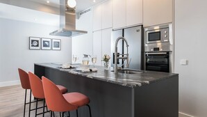 A modern kitchen with a central island, stainless steel appliances, and a minimalist design. - Alcala IX - Three Bedroom Apartment, Sleeps 6 (Madrid)