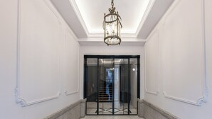 A hallway with a marble floor, a chandelier, and a glass door leading to a staircase. - Alcala IX - Three Bedroom Apartment, Sleeps 6 (Madrid)