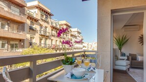 A balcony with a table set for two, a potted plant, and a view of a residential building. - General Pardiñas III (Madrid)