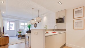 A modern kitchen with a central island, pendant lighting, and a microwave. - General Pardiñas III (Madrid)