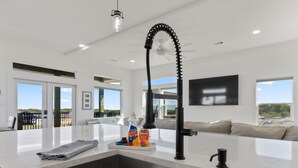A modern kitchen with a stainless steel sink, a faucet, and a bottle of Ajax dish soap. - Modern Matagorda Getaway – 4 King Bedrooms, Canal Access & Minutes to the Beach (Matagorda)