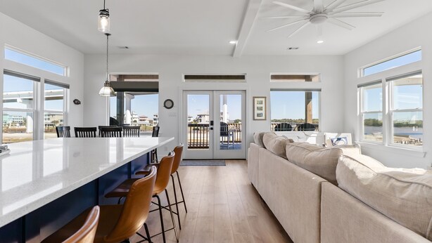 A modern kitchen with a large island, bar stools, and a view to the outside. - Modern Matagorda Getaway – 4 King Bedrooms, Canal Access & Minutes to the Beach (Matagorda)