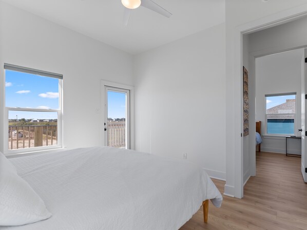 A bedroom with a large bed, a door leading to a balcony, and a view of the sea. - Modern Matagorda Getaway – 4 King Bedrooms, Canal Access & Minutes to the Beach (Matagorda)