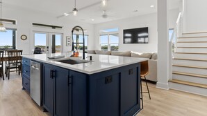 A modern kitchen with a large island, built-in appliances, and a view to the outdoors. - Modern Matagorda Getaway – 4 King Bedrooms, Canal Access & Minutes to the Beach (Matagorda)