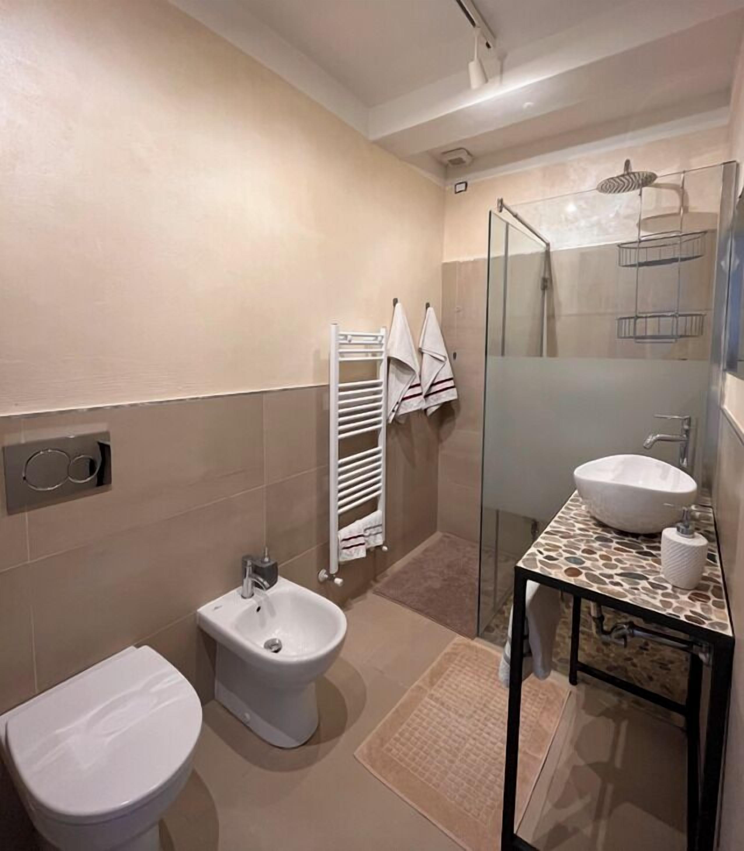 Une salle de bain moderne équipée d’un bidet, de toilettes et d’une douche à l’italienne.