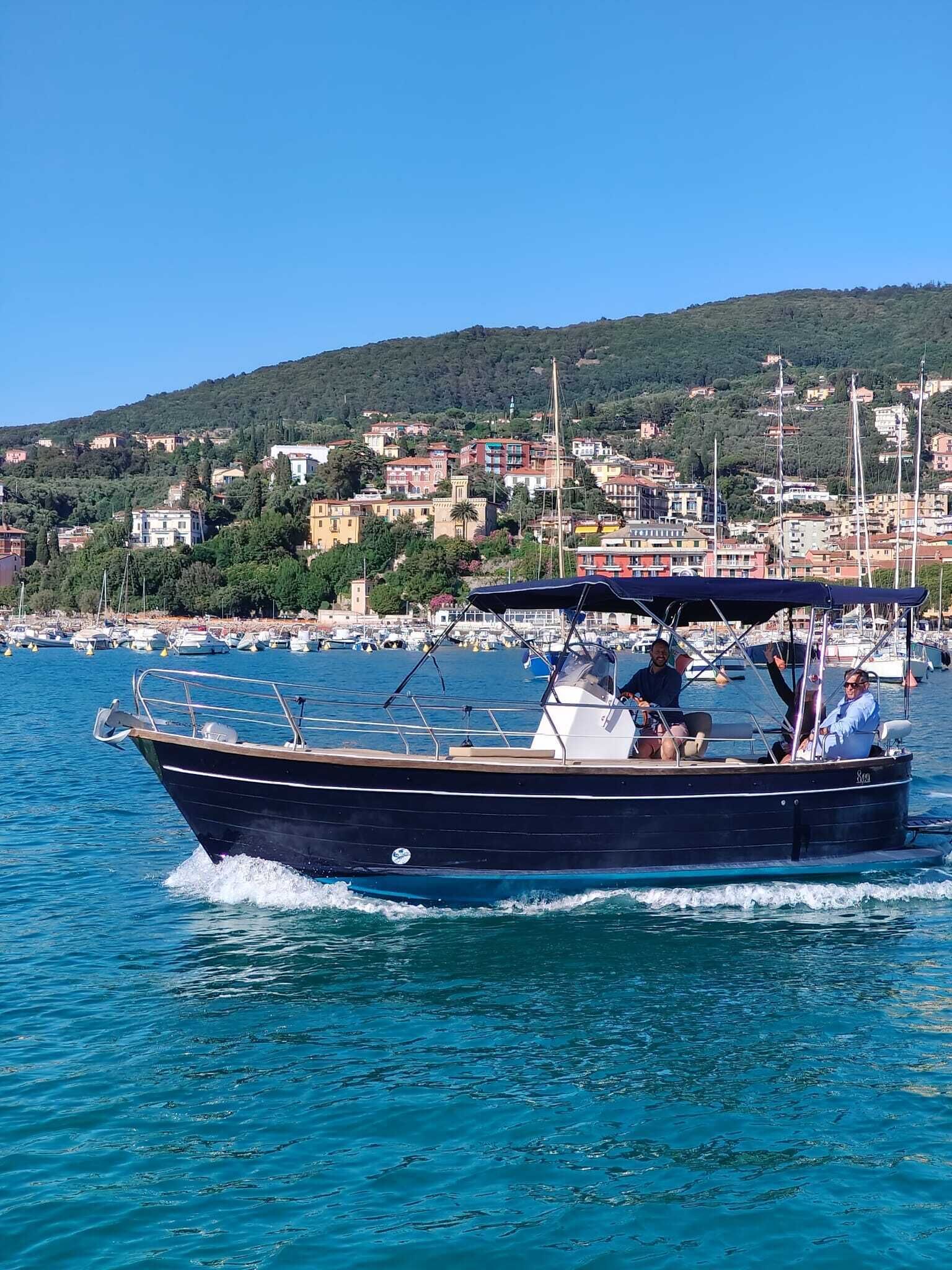 Un bateau navigue dans une marina, avec en arrière-plan une ville côtière.