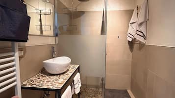 Un baño moderno con ducha envuelta en vidrio, lavamanos independiente y bañera.