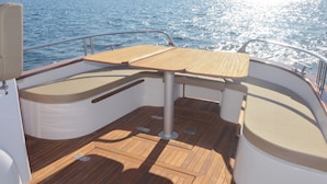 A boat's deck with a central table, cushioned seating, and a metal railing. - Collimare rooms (Vezzano Ligure)