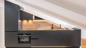 A modern kitchen with built-in appliances, a wooden countertop, and a sleek black cabinetry design.