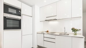 Une cuisine moderne avec des meubles blancs, un four Bosch, un réfrigérateur et un évier agrémenté d’un vase de fleurs.