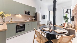 Et moderne køkken med spiseplads, med et rundt bord med stole, indbygget ovn og køleskab.