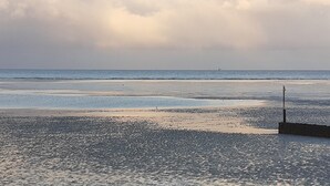A beach with a sandy shore and a pier extending into the water. - Fokuhl Apartment with Shared Garden, Balcony, and Wi-Fi (Hooksiel)