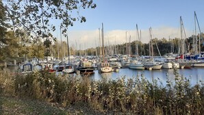 A marina with various boats docked, surrounded by trees and vegetation. - Fokuhl Apartment with Shared Garden, Balcony, and Wi-Fi (Hooksiel)