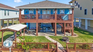 A two-story building with a balcony, a covered patio, and a satellite dish. - Colorado Riverfront Oasis – Fishing, Views & Perfect Family Getaway (Matagorda)