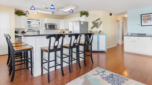 A modern kitchen with white cabinets, a central island with bar stools, and pendant lighting. - Colorado Riverfront Oasis – Fishing, Views & Perfect Family Getaway (Matagorda)