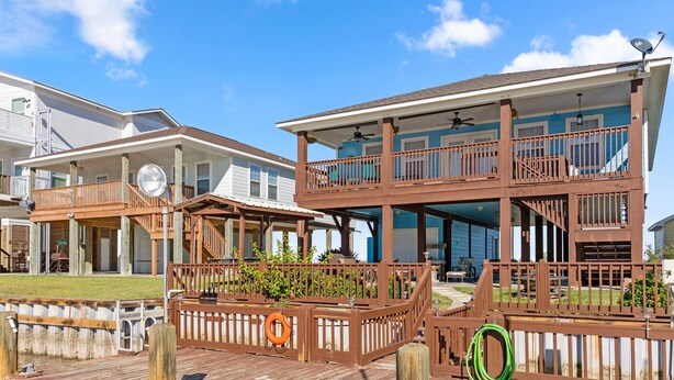 A two-story wooden building with a balcony and a covered deck area. - Colorado Riverfront Oasis – Fishing, Views & Perfect Family Getaway (Matagorda)
