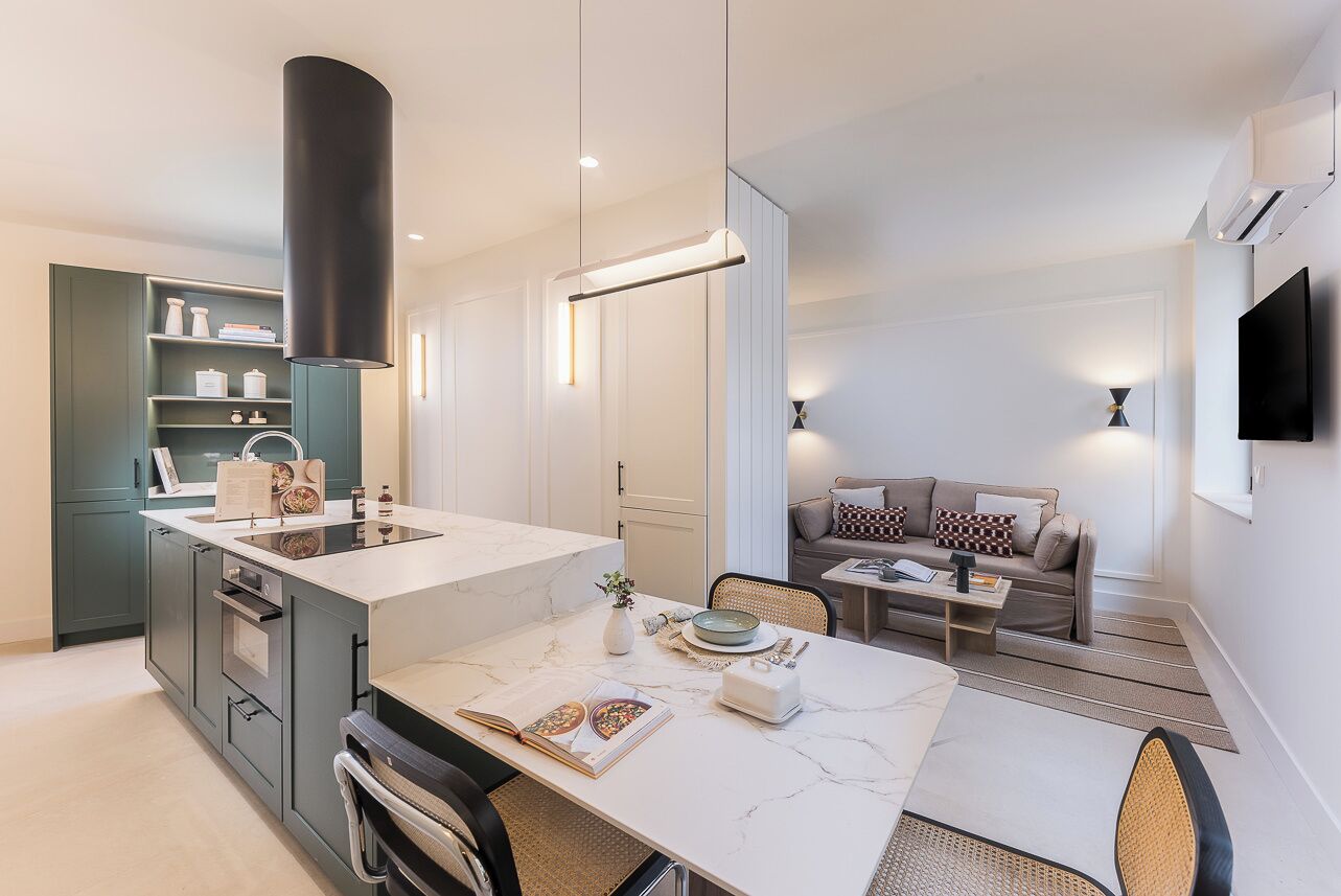 Een moderne keuken met een marmeren aanrecht, een ingebouwde oven en een eethoek met een tafel en stoelen.