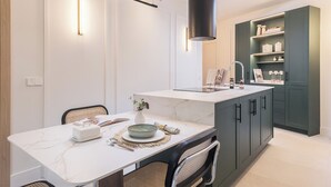 A modern kitchen with a white marble countertop, dark cabinetry, and a built-in sink. - Ramón de Santillán II (Madrid)