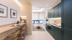A modern kitchen with dark cabinets, a wooden countertop, and a dining area with chairs. - Ramón de Santillán I (Madrid)