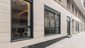 A building facade with large windows, a tiled ground floor, and a brick upper level. - Ramón de Santillán I (Madrid)