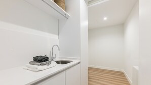 Una cocina moderna con armarios blancos, un lavamanos de acero inoxidable y piso de madera.