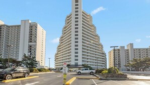 Un immeuble moderne de grande hauteur, doté d’un design incurvé original, et entouré d’autres bâtiments similaires.