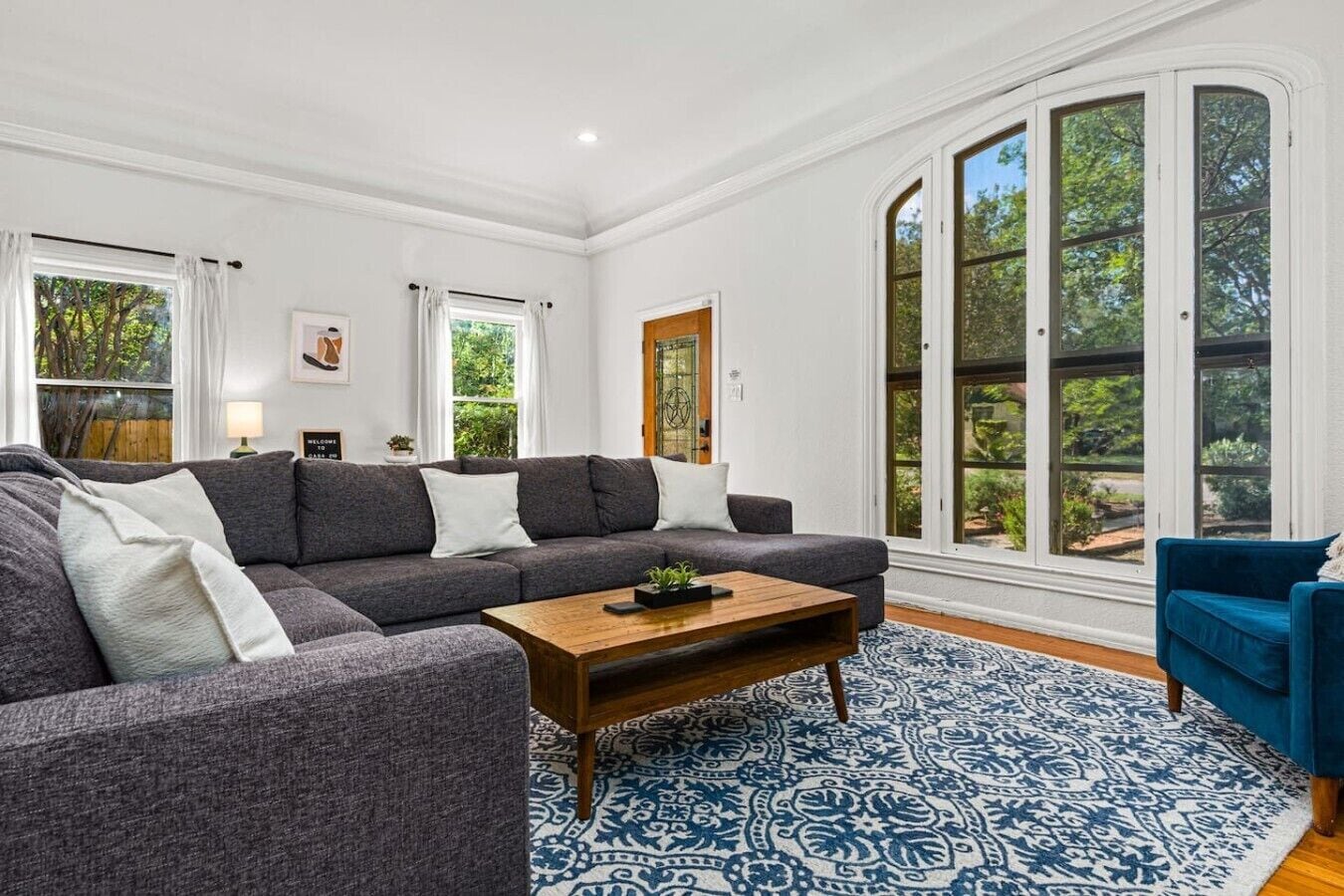 A modern living room with a sectional sofa, a coffee table, and a blue armchair.